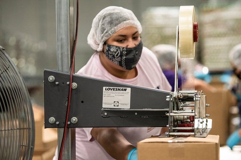 Protected production worker operating automated packaging equipment